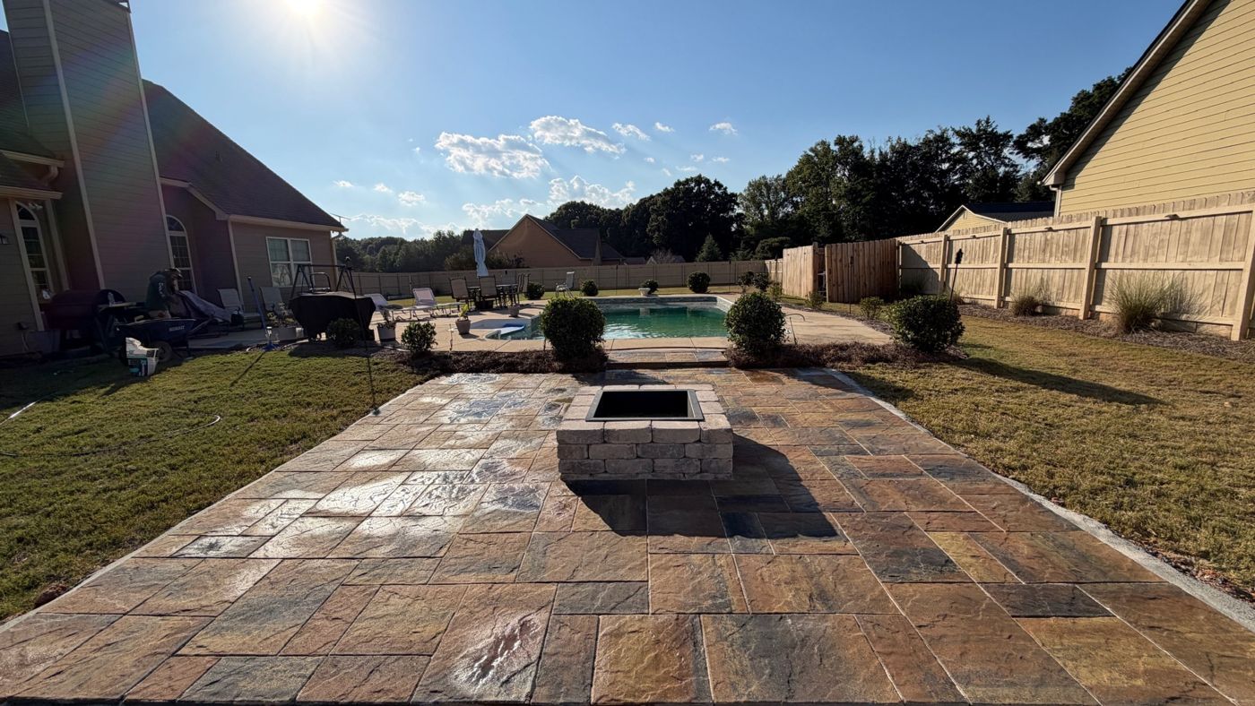 Finished paver patio with block fire pit beside a pool