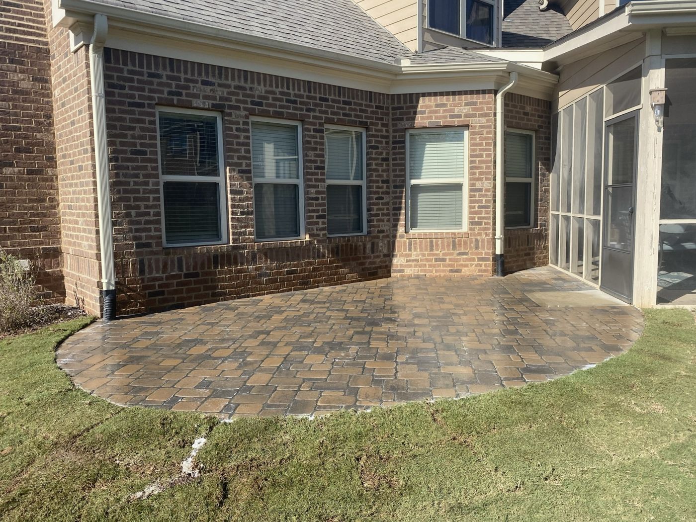 Curved paver patio installed beside a brick home by Green Wave