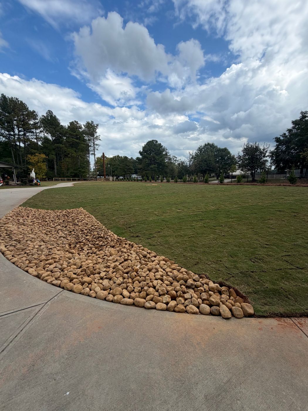 Fresh sod lawn with a river rock border along a curved driveway